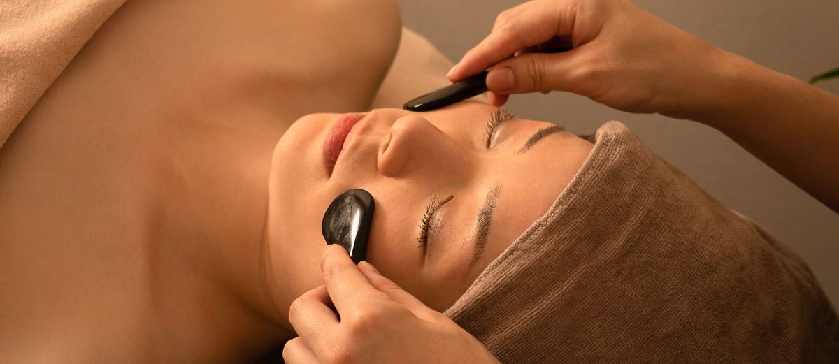 Two smooth dark stone tools drawn along the brow and cheek of a face at rest.